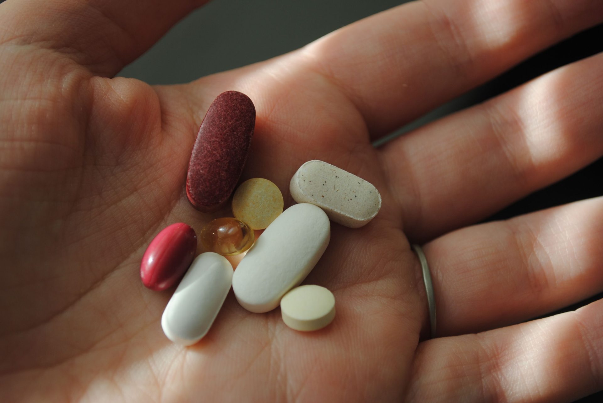 Eine Nahaufnahme verschiedener Pillen und Vitamine, die in einer Hand gehalten werden.