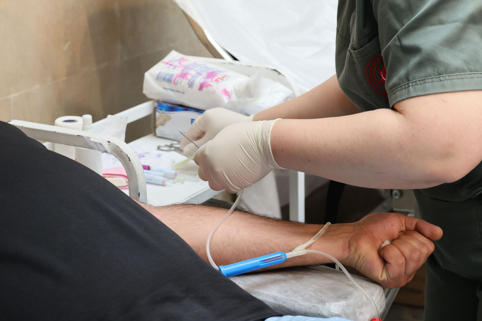 Eine medizinische Fachkraft nimmt einem Patienten in einer klinischen Umgebung Blut aus dem Arm ab.