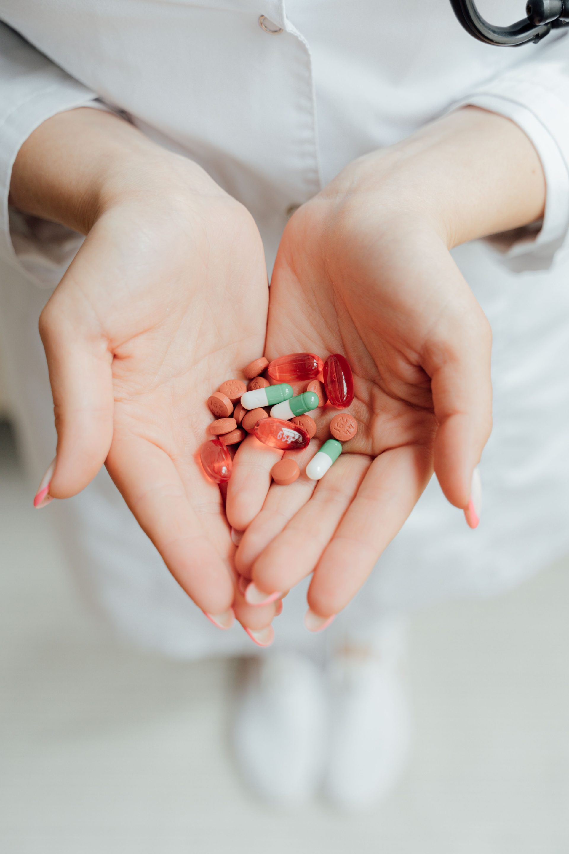 Nahaufnahme einer Person, die verschiedene Tabletten und Kapseln in den Händen hält – ein Symbol für Gesundheitsversorgung und Medizin.