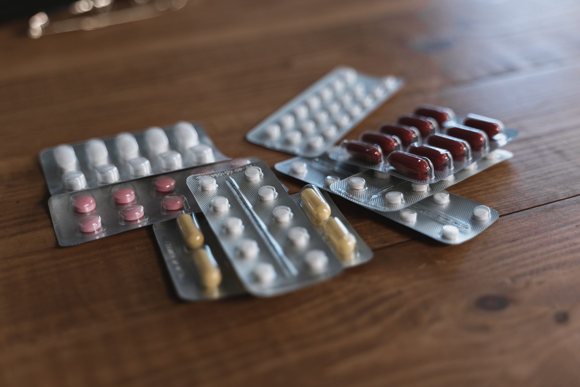 Verschiedene Tabletten in Blisterpackungen, präsentiert auf einer Holzoberfläche. Ideal für Inhalte rund um das Thema Gesundheit.
