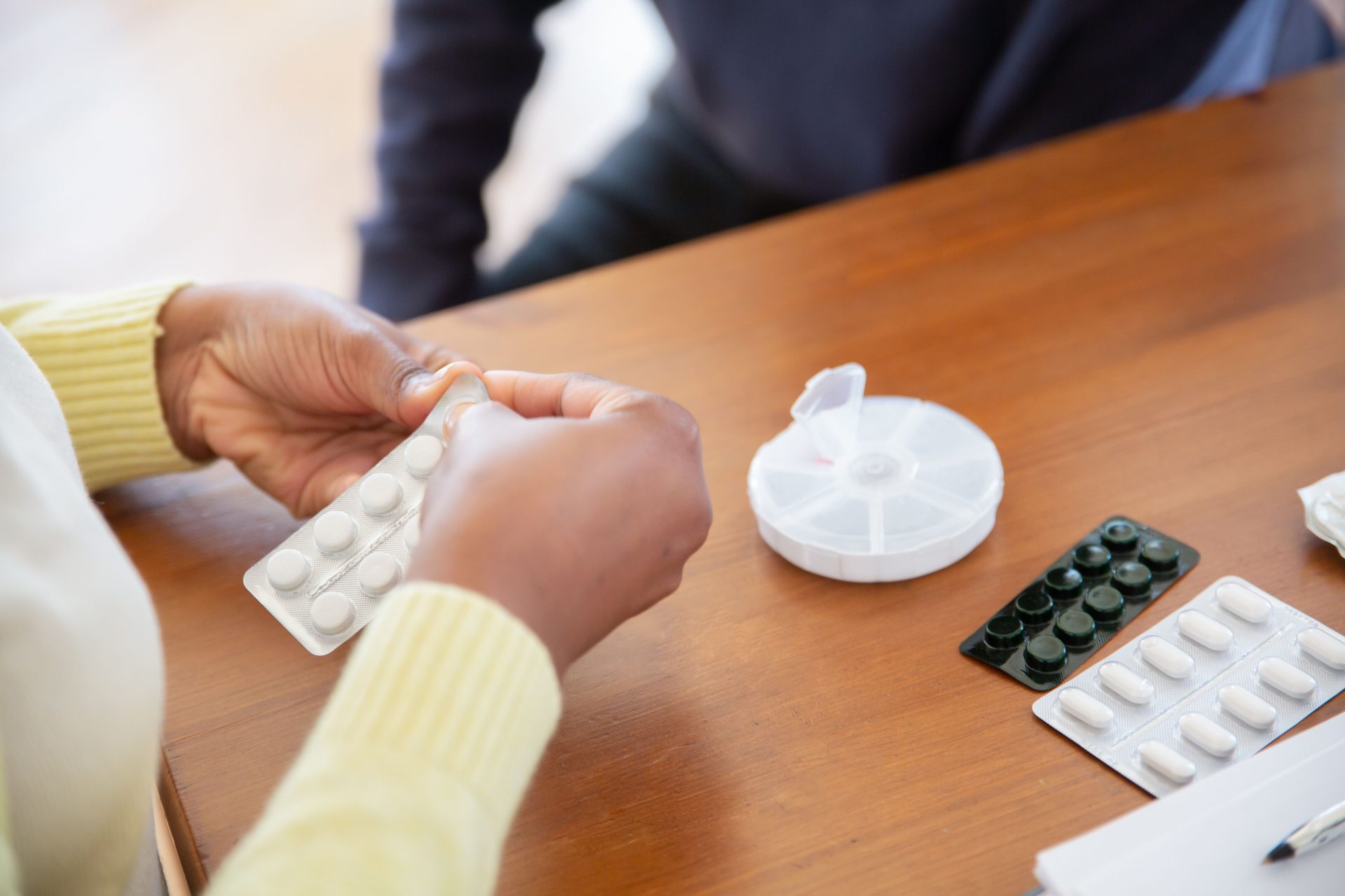 Nahaufnahme einer Pflegekraft, die in einer Pflegeeinrichtung Tabletten und Medikamente auf einem Tisch ordnet.