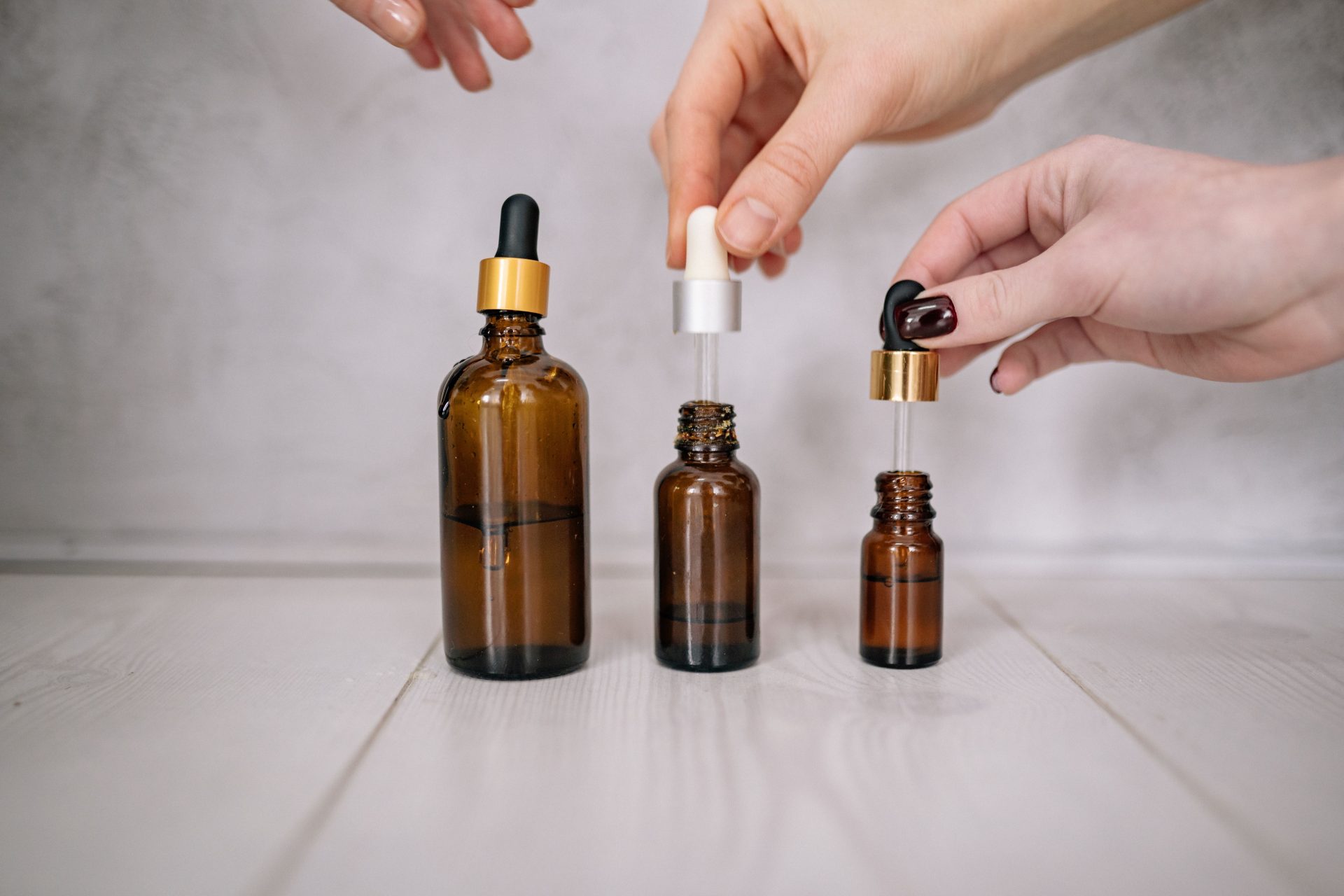 Nahaufnahme von Händen, die braune Flaschen mit Pipetten halten – ideal für Themen rund um Hautpflege und Aromatherapie.